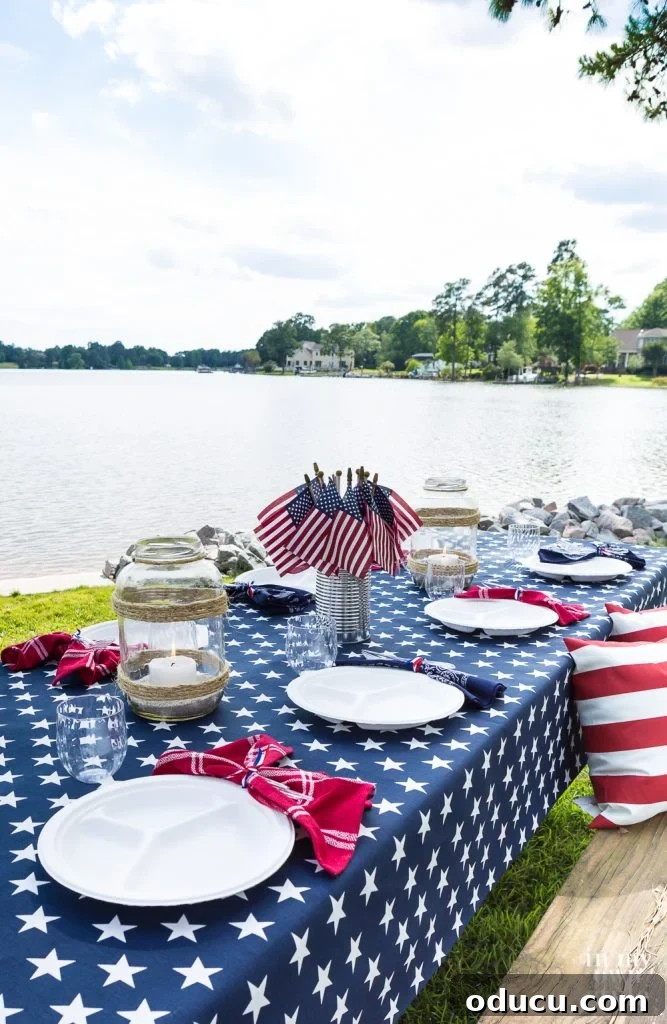 The Style Edit, Vol. 12 2 A beautifully set picnic table beside a tranquil lake, adorned with patriotic decor, perfect for a 4th of July celebration or any summer gathering.