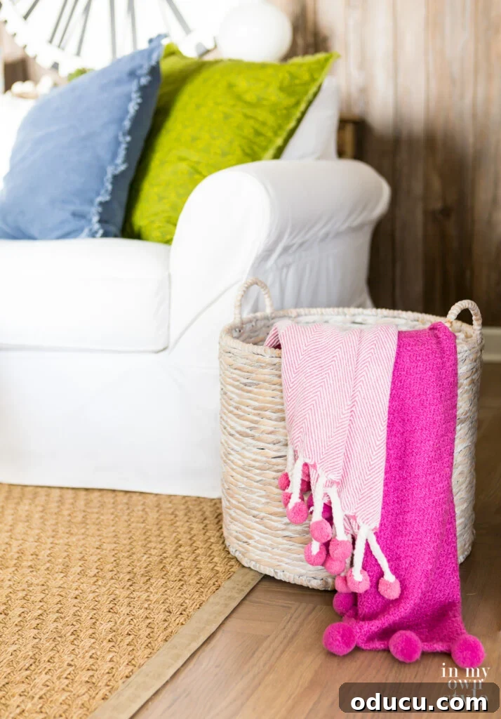 Statement Decor: Creative Ways with Large Baskets 11 A large floor basket in a cozy living room, elegantly holding two throw blankets draped over its side, adding comfort and style.