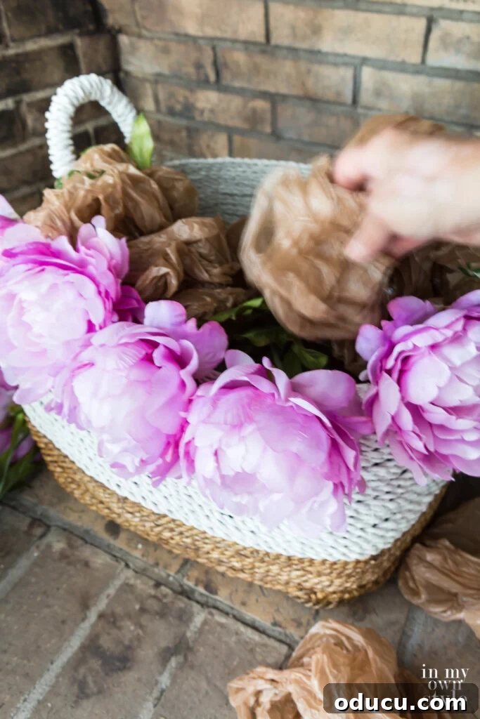 Statement Decor: Creative Ways with Large Baskets 4 Demonstration of stuffing a large decorative basket with balled-up plastic bags to create a full base before arranging faux flowers.