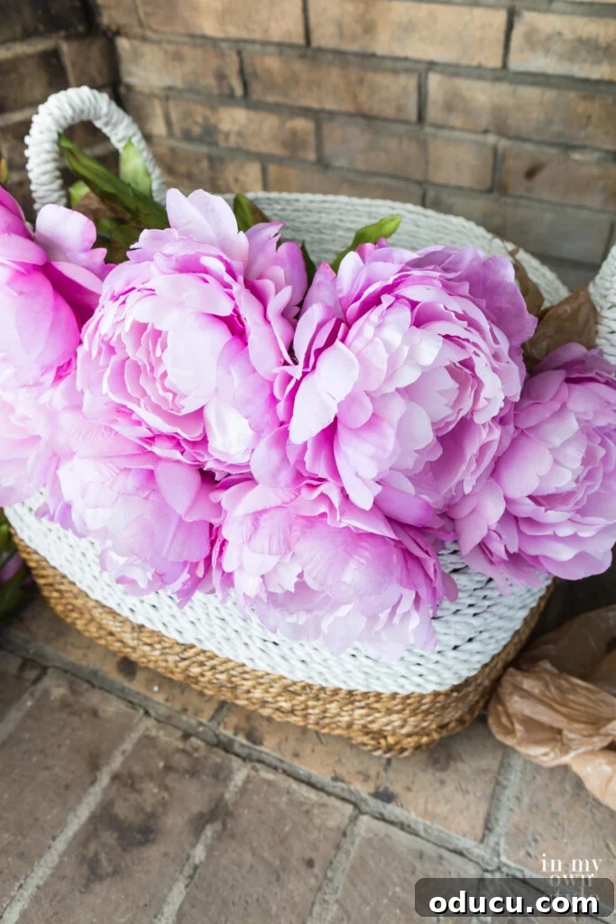 Statement Decor: Creative Ways with Large Baskets 5 A large decorative basket in an empty fireplace brimming with vibrant faux pink peonies, creating a stunning summer decorating focal point.
