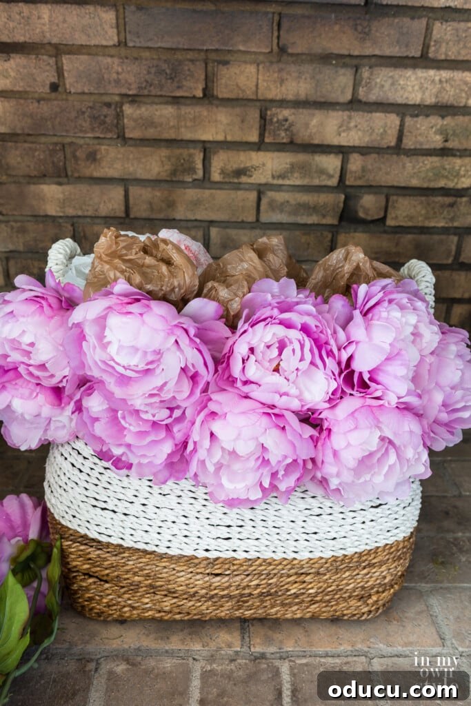 Statement Decor: Creative Ways with Large Baskets 6 Process of filling a large decorative basket with faux pink peonies, using balled-up plastic bags as filler to achieve a full and lush appearance.
