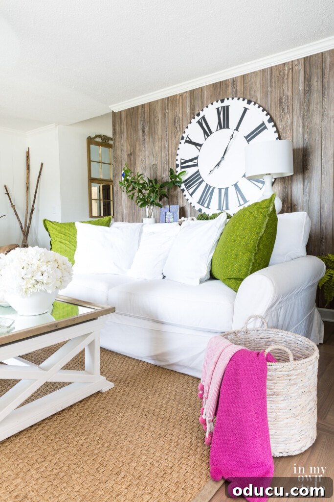 Effortless Summer Style 15 Summer decorating White sofa with green pillows in living room with faux barnwood paneling on wall.