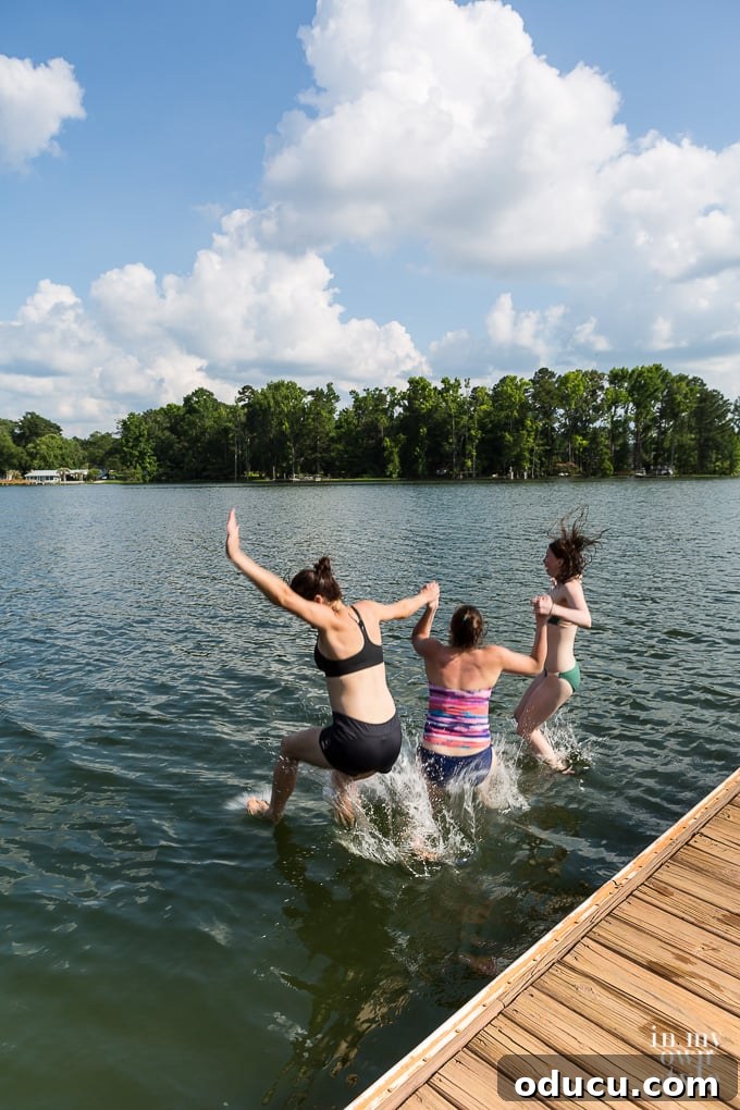 Effortless Summer Style 3 3 girls holding hands while jumping onto a lake from a dock.
