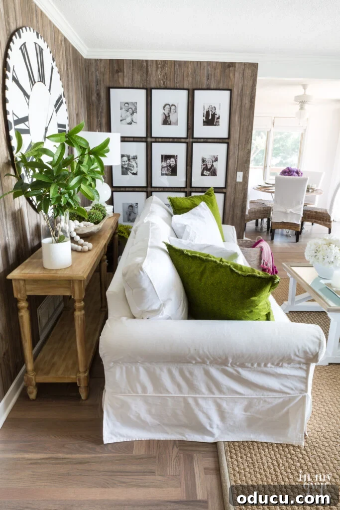 Effortless Summer Style 6 Decorating for summer color scheme. Faux barnwood paneled wall in living room with photo gallery, white sofa with green pillows and seagrass rug.