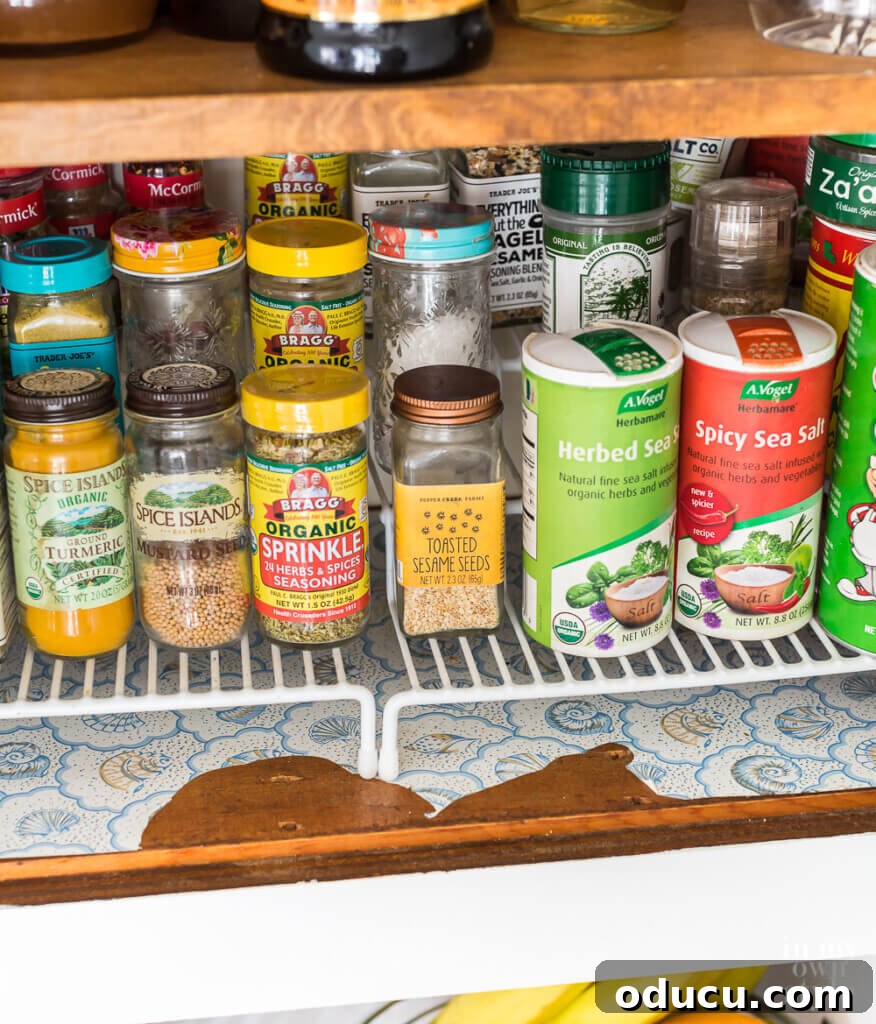 Brighten Your Kitchen with DIY Colorful Cabinet Liners 3 Before image showing spice cabinet with old ripped adhesive shelf lining paper.