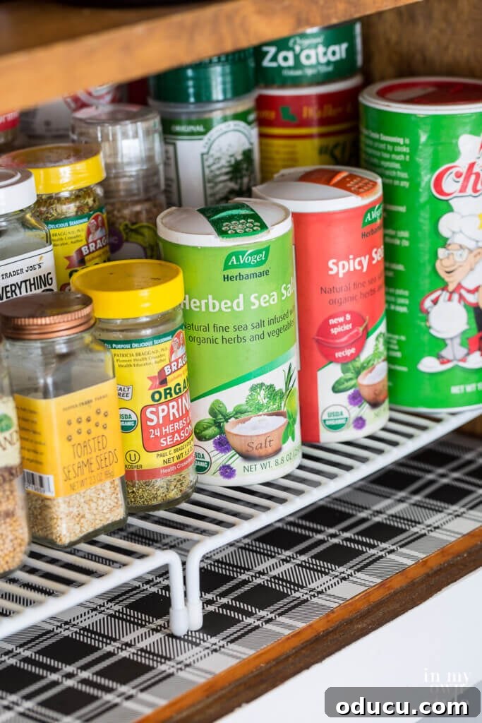 Brighten Your Kitchen with DIY Colorful Cabinet Liners 4 Spice cabinet in kitchen with black and white plaid cut to fit non adhesive shelf paper.