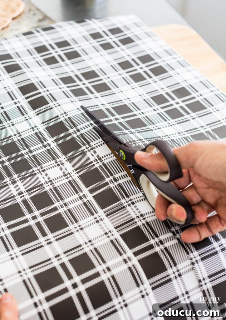 Brighten Your Kitchen with DIY Colorful Cabinet Liners 6 Cutting wipeable gift wrap with scissors.