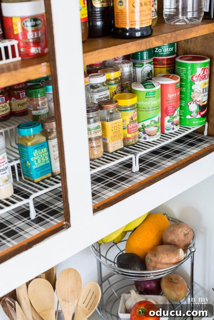 Brighten Your Kitchen with DIY Colorful Cabinet Liners 7 Open kitchen cabinet showing gift wrap made into kitchen shelf liner. Black and white plaid design.