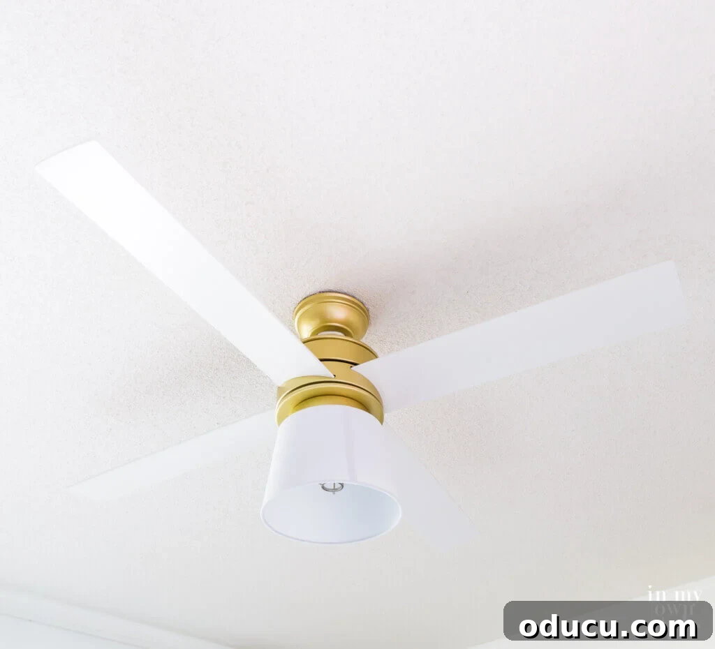 Ceiling Fan Globe Upgrade Choices 10 The Hunter Hepburn ceiling fan in white, showcasing the elegant DIY replacement globe crafted from a white lampshade, viewed from a distance.