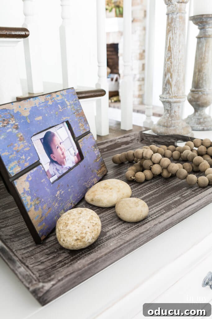 Entryway Upgrade: The Dresser Solution 12 Purple distressed photo frame on tray with rocks and a wood bean garland for fall decor.