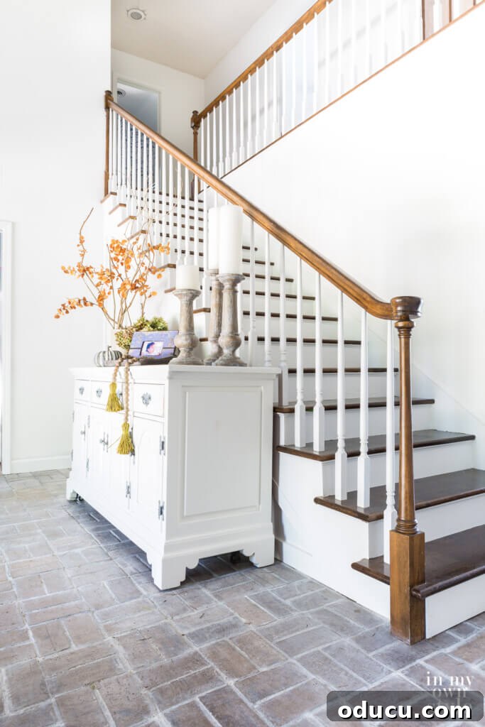 Entryway Upgrade: The Dresser Solution 14 White sideboard decorated for fall in two story entry, showcasing various decor elements.