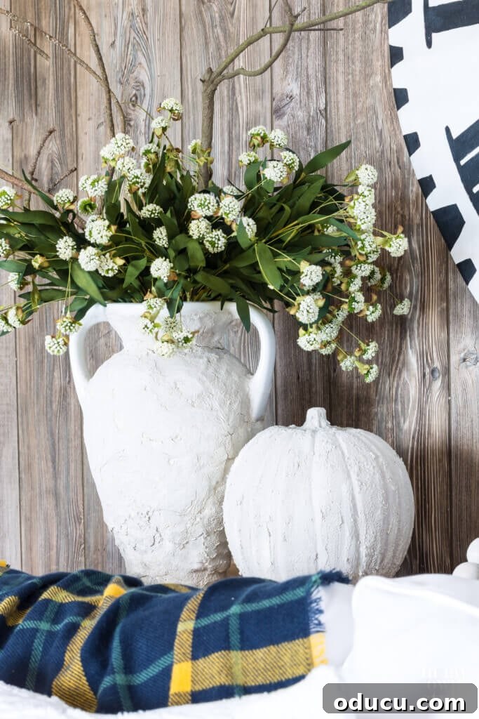 Autumn's Embrace: Natural Decor for Your Living Space 18 Fall Vase and pumpkin made to look like plaster. Vase filled with white flowers.