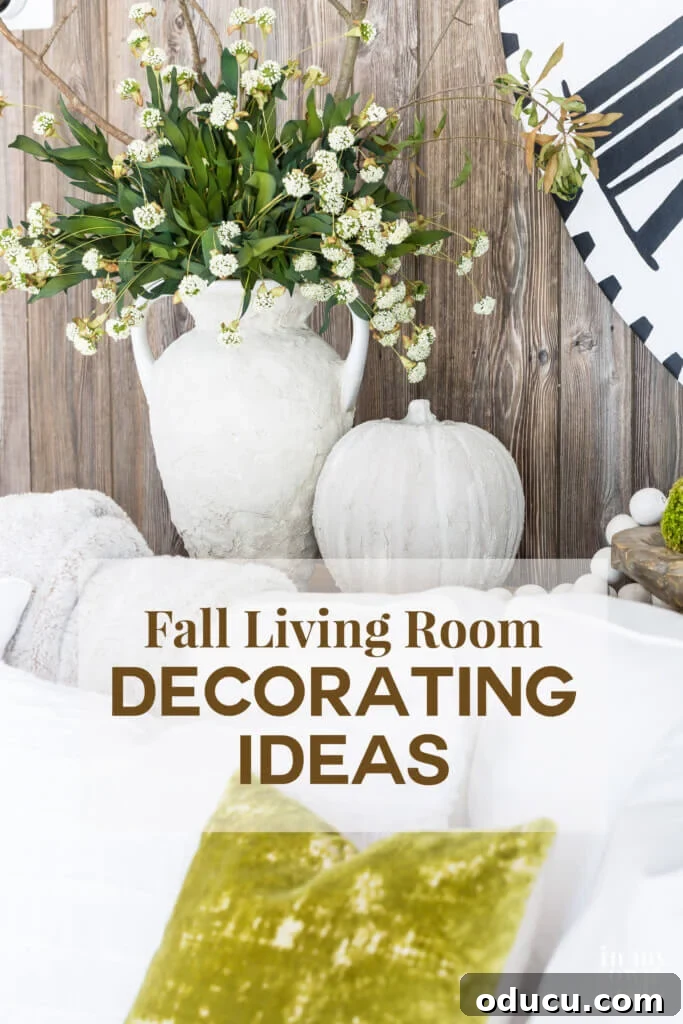 Autumn's Embrace: Natural Decor for Your Living Space 22 A stone vase and pumpkin on a sofa table with faux barn wood paneling behind them. Text says Fall Living Room Decorating Ideas