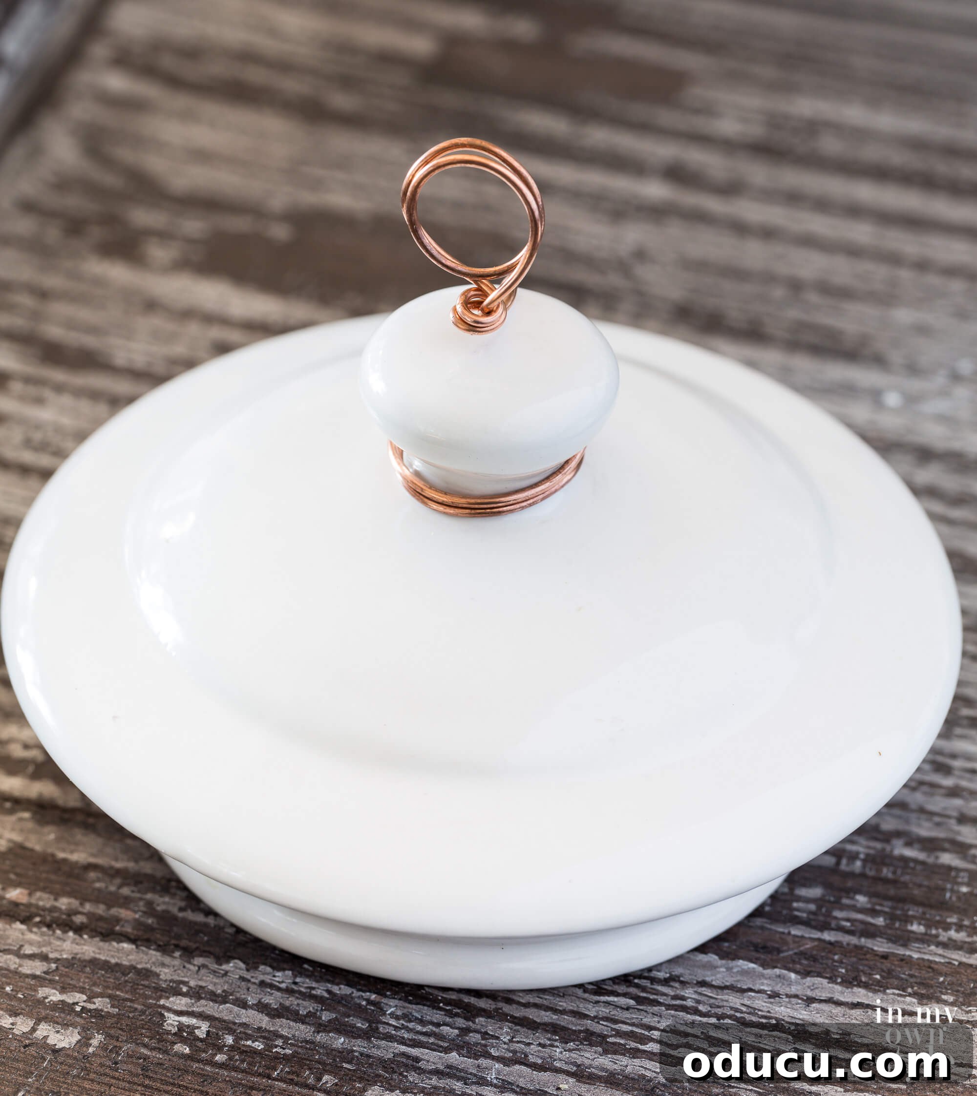 A striking image of a finished white ceramic teapot lid photo holder, elegantly standing on a surface, fully prepared to display a photograph.