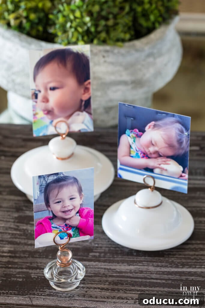 A stunning arrangement of upcycled photo holders, crafted from ceramic and glass jar lids, displaying a variety of cherished photos on a stylish tabletop. This showcases creative and frame-free photo display methods.