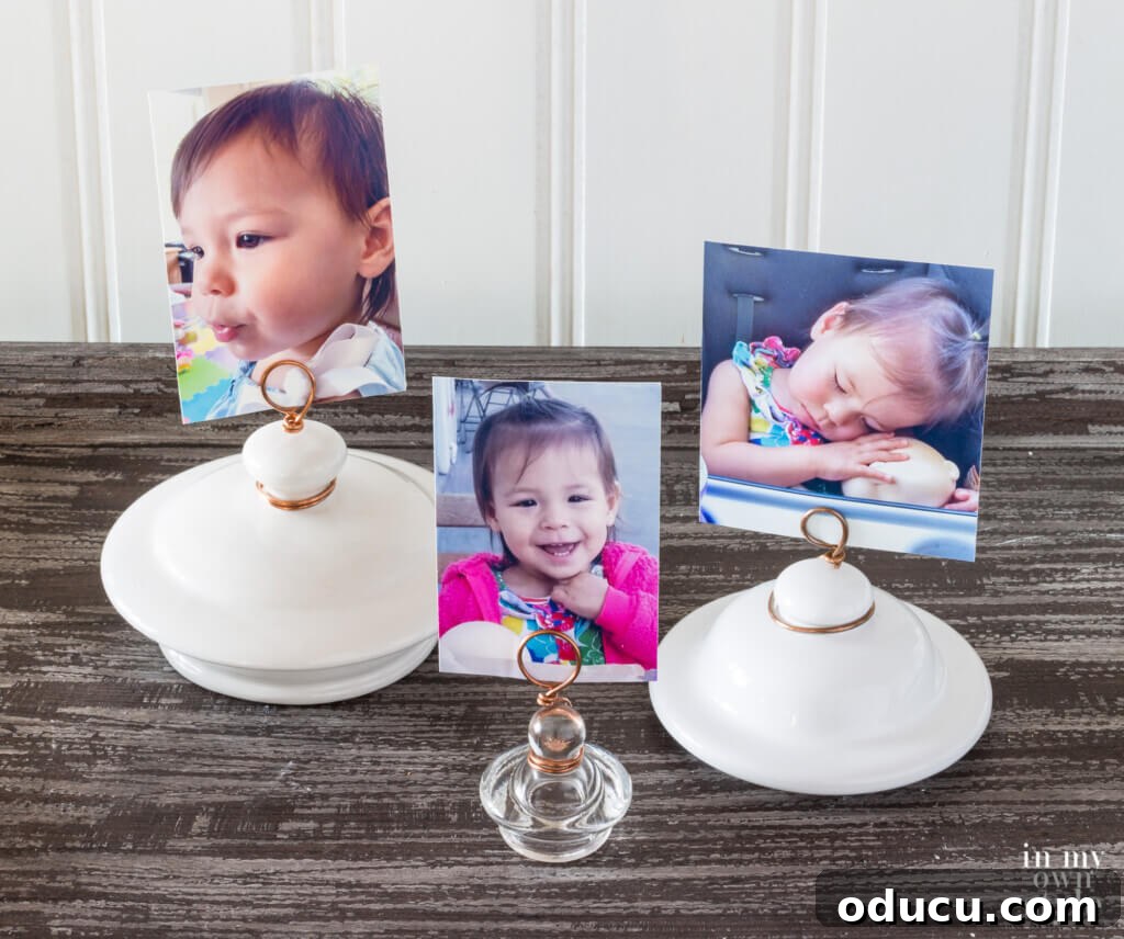 A beautiful display of three finished photo holders, ingeniously crafted from ceramic or glass jar lids, elegantly showcasing cherished photographs on a textured surface.