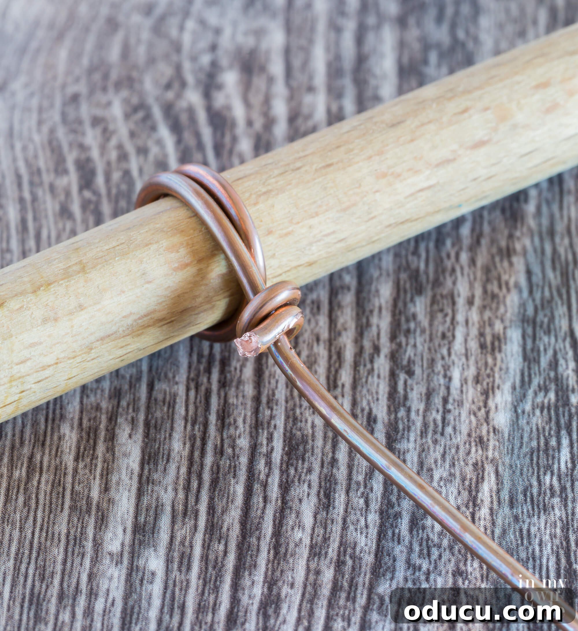 Detailed image illustrating the process of creating the round wire photo clip loops by wrapping wire around a dowel as a shaping tool.