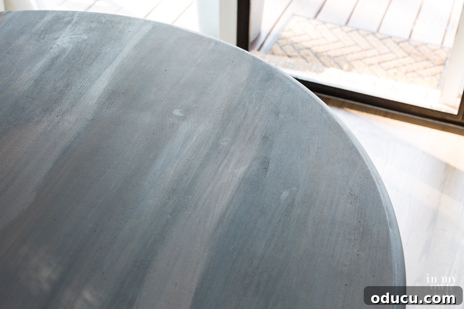A layered surface with truffle brown chalk paint being partially wiped away over a black base, demonstrating the technique for achieving transparent, aged effects in a faux zinc finish. The dark background is still visible through the brown.