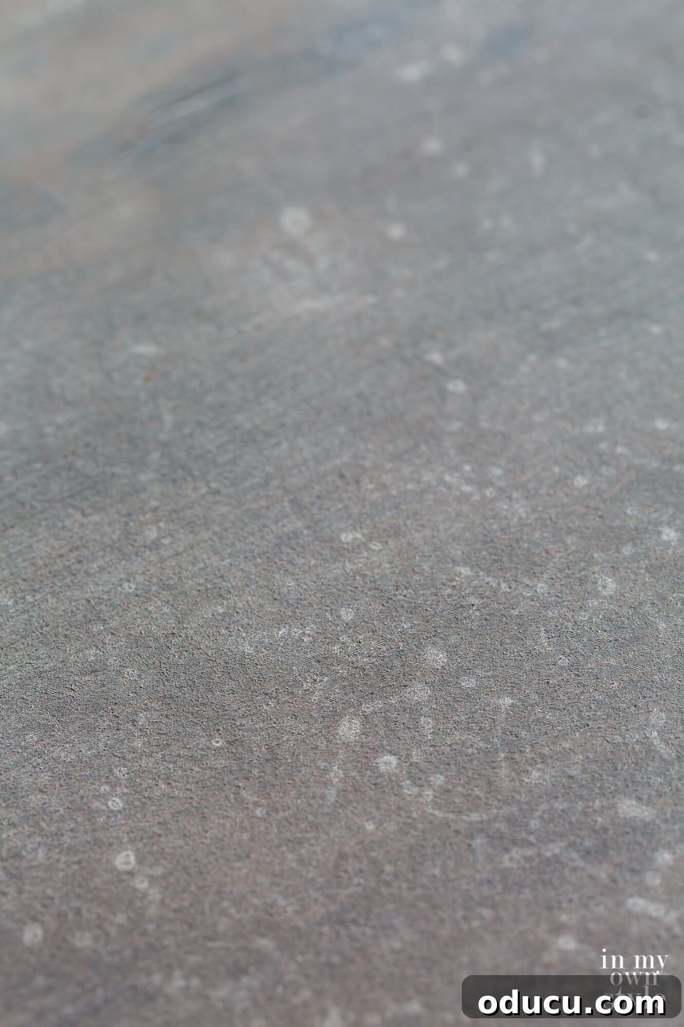 A close-up view of the evolving faux painted zinc finish, showcasing the intricate details and layered textures created by the application and blending of grey and other colors. The surface begins to truly resemble aged metal.