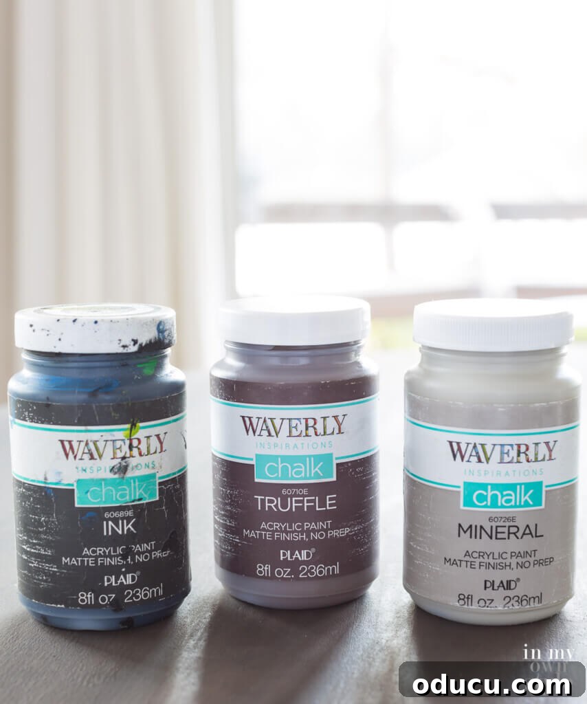 Zinc Effect Wooden Table Surfaces 8 A selection of Waverly Inspirations Chalk paint colors, including Ink (black), Truffle (brown), and Mineral (light grey), specifically chosen and displayed for creating the faux zinc finish. White paint is also used but not pictured.