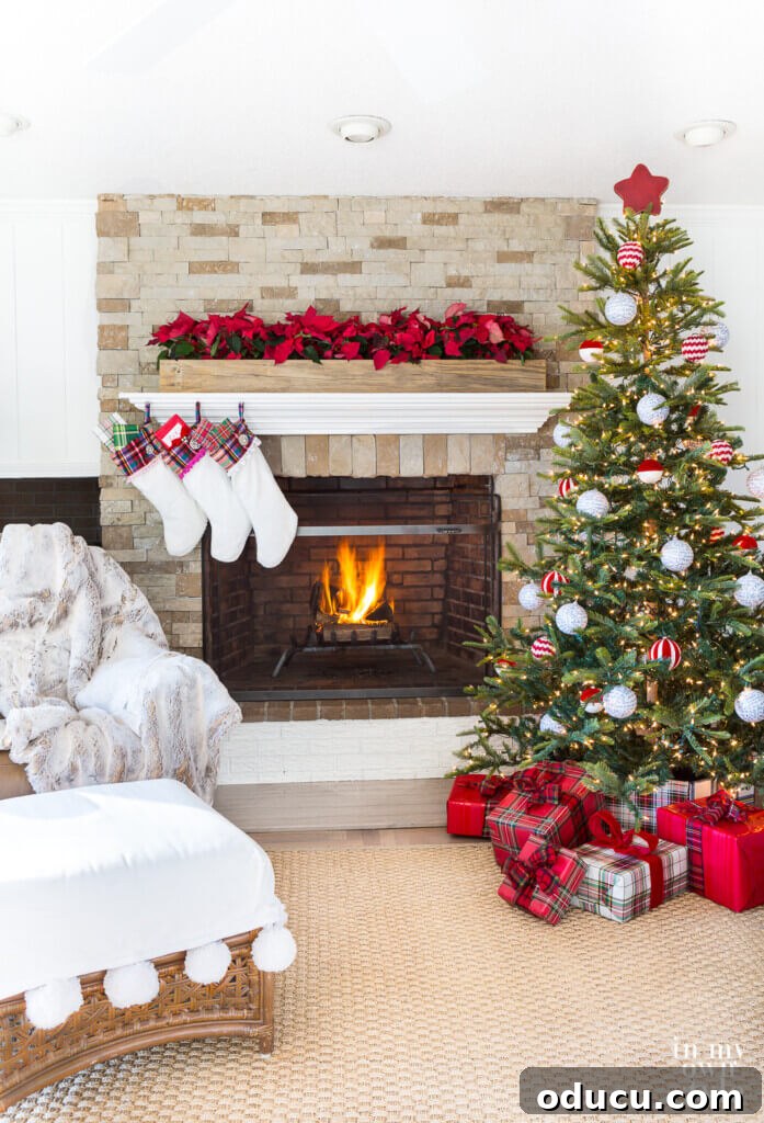 Effortless Festive Home Styling 12 A beautifully decorated Christmas mantel in a cozy living room, featuring a rustic wooden planter box filled with vibrant poinsettias and a festive red tree topper.