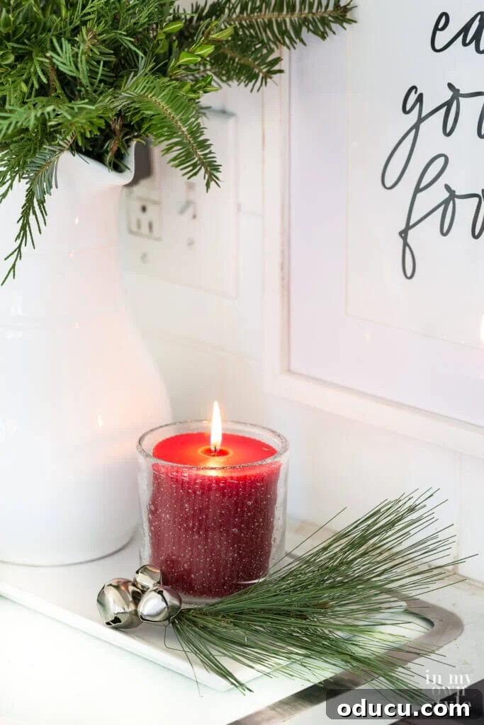 Effortless Festive Home Styling 24 A simple yet elegant Christmas decorating detail: a tray holding a lit candle, nestled amongst sprigs of fresh pine, and adorned with delicate jingle bells, creating a cozy vignette.