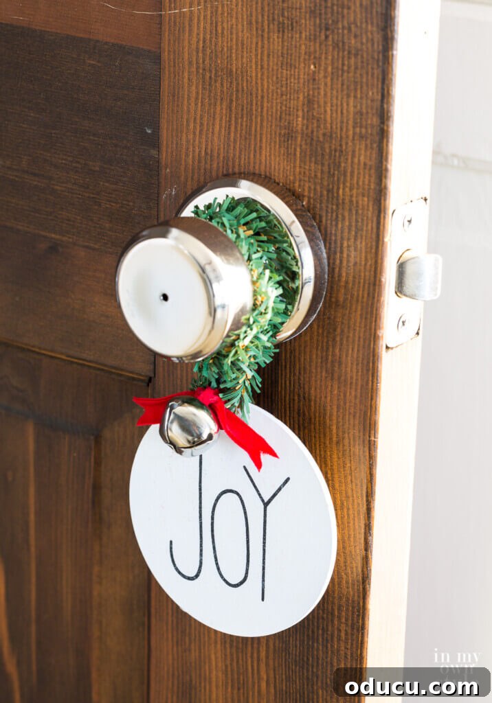 Effortless Festive Home Styling 28 A festive Christmas ornament tied with red ribbon and jingle bells, serving as a charming and audible doorknob accent, creating an inviting holiday welcome.