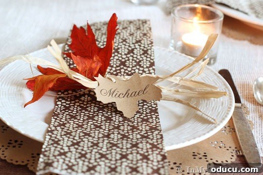 Effortless Thanksgiving Place Card Ideas for a Memorable Table 9 Rustic leaf place card made from Kraft paper, tied with raffia, elegantly displayed on a Thanksgiving table setting.