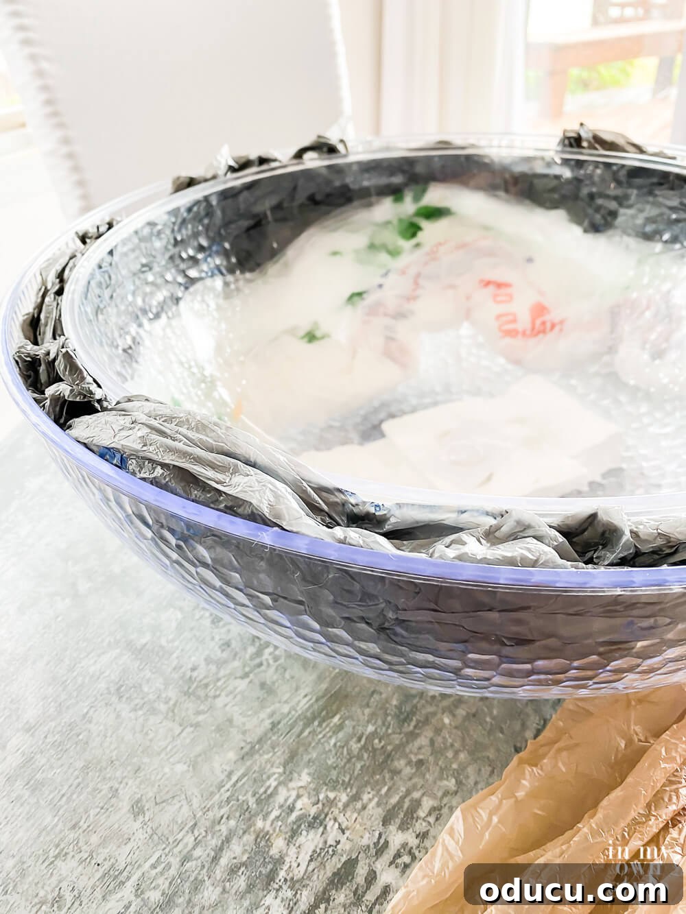 The area between the plastic bowls is being filled with crumpled plastic grocery bags, adding lightweight bulk.