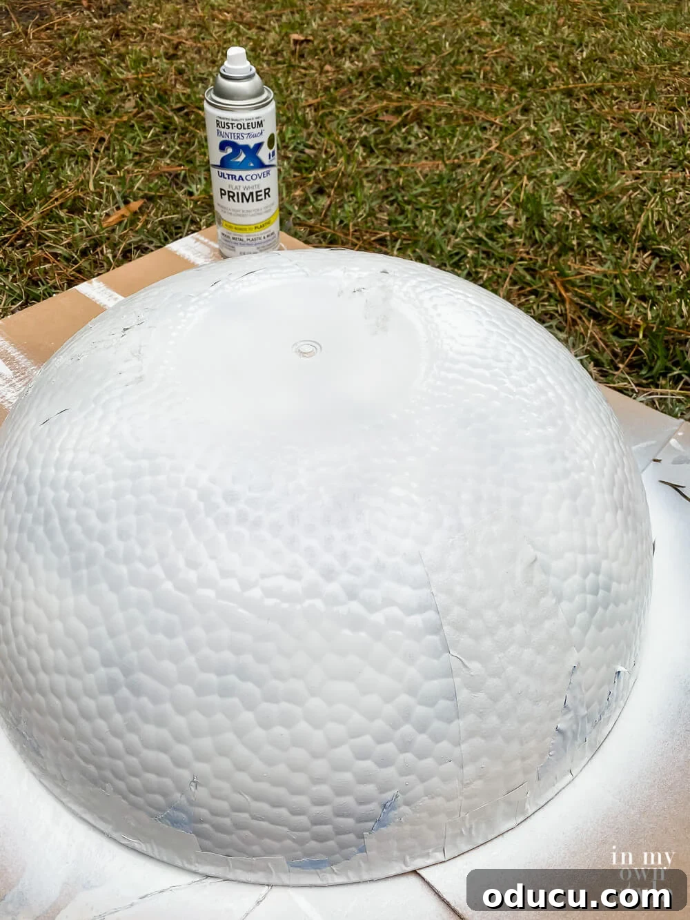 Spray painting primer onto the large clear plastic bowls to prepare them for the faux stone finish.