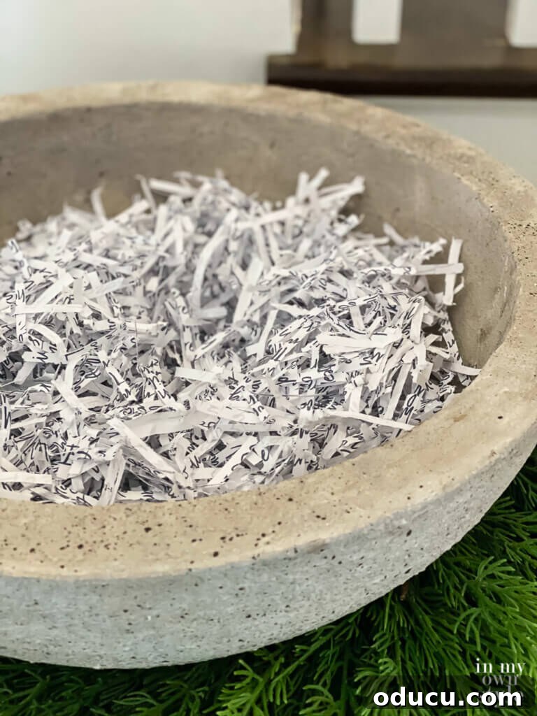 Shredded paper forms a base within a faux cement-look large bowl, ready for decorative fillers.
