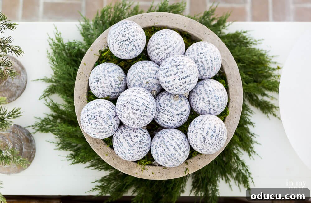 Large DIY fake concrete planter filled with elegant white ornaments and handwritten script, resting on a cedar wreath.