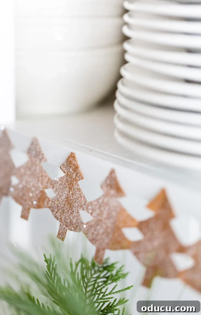 Uncharted Style 2 Close up image of a paper chain of pine trees decorating the edge of kitchen shelves for the holidays, adding a festive touch to home decor.