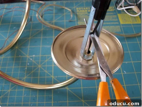 Detailed shot of cutting electrical wires from a chandelier's candle holder, a key step in transforming it into an outdoor candle fixture.