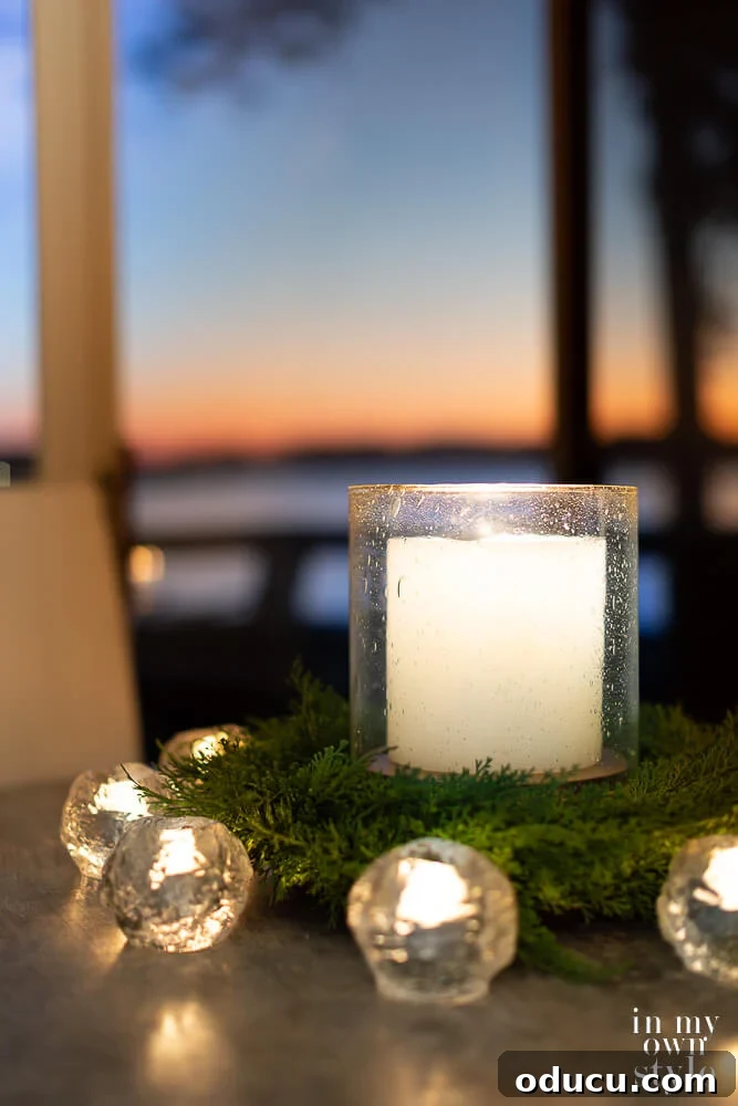 Large candle in seeded glass hurricane on kitchen table with smaller candles around it to provide cozy light.