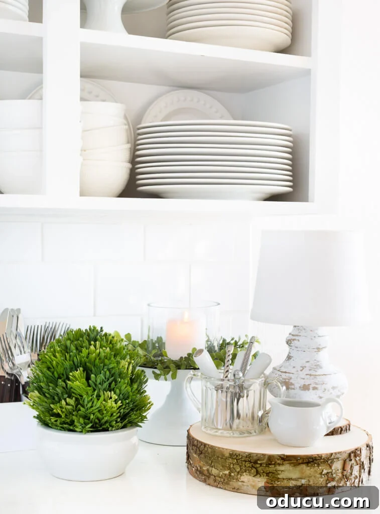 After Christmas decorating ideas for the kitchen. White kitchen with greenery and white plates and dishes on a counter.
