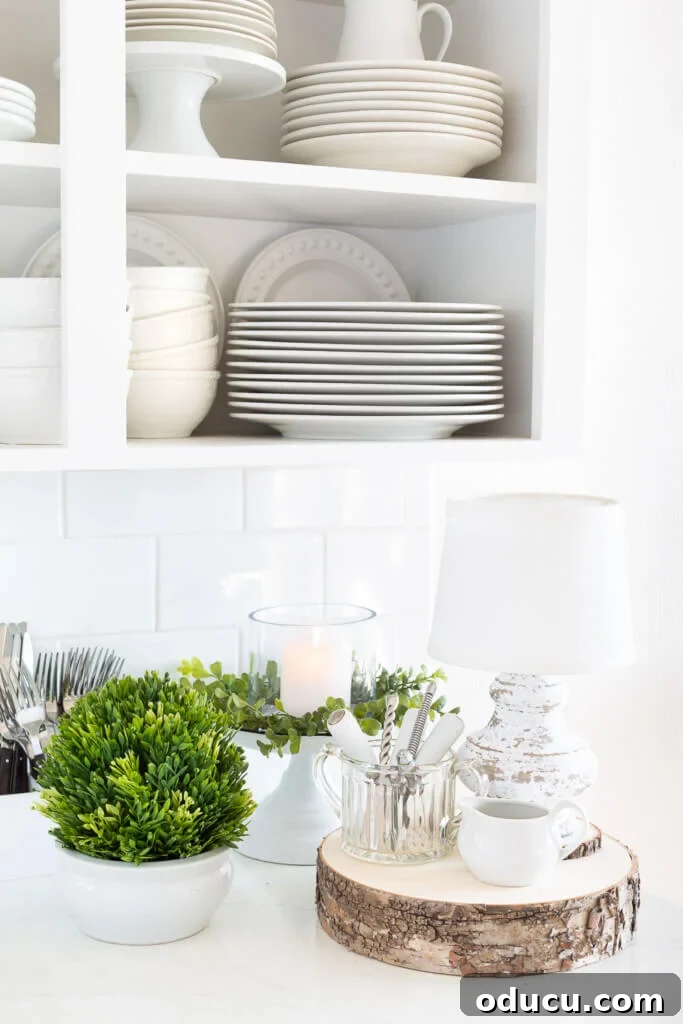 Cozy Winter Decor Beyond the Holidays 11 After Christmas decorating ideas for the kitchen. White kitchen with greenery and white plates and dishes on a counter, creating a fresh look.