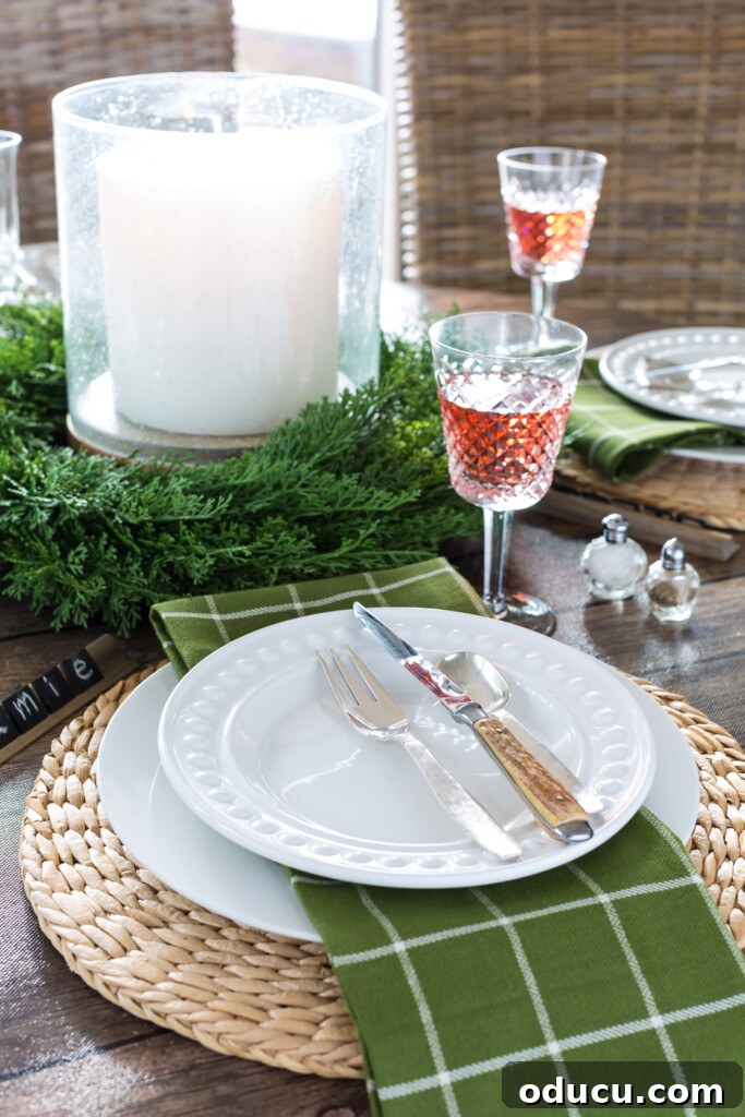 Cozy Winter Decor Beyond the Holidays 12 Round dining table set for a Christmas dinner using white plates and olive green napkins, evoking a festive yet cozy atmosphere.