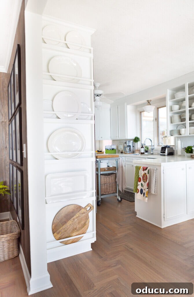 DIY Floor-to-Ceiling Wall Plate Rack 4 Custom-built white wooden plate rack wall, separating living room and kitchen, showcasing elegant plate display.