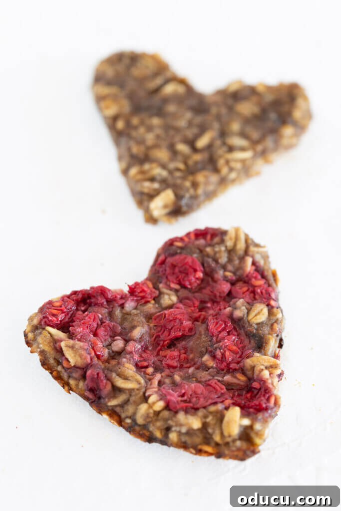 Wholesome Vegan Banana Oat Delights 6 Two perfectly flat heart-shaped banana oatmeal cookies, adorned with berries, ready for a special occasion.