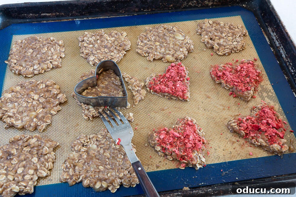 Wholesome Vegan Banana Oat Delights 7 Heart-shaped cutout cookies on a baking sheet, precisely formed and ready to be baked to perfection.