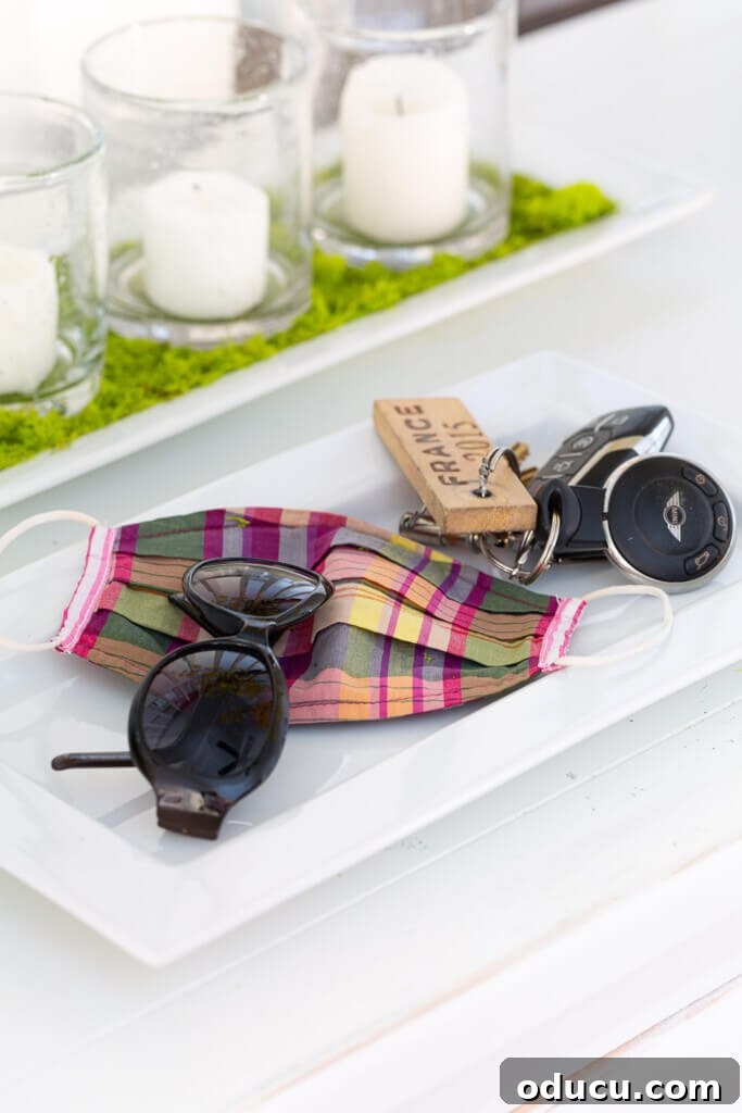 Blossom Your Entryway This Spring 7 White ceramic tray on a console table holding sunglasses, keys, and a plaid face mask.