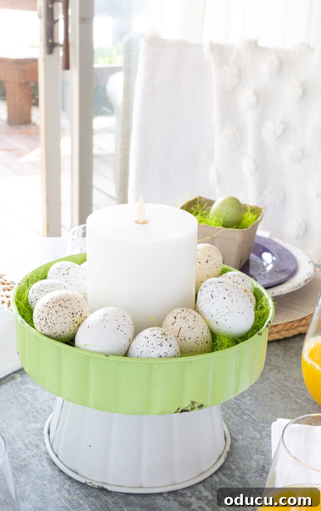Easter brunch table centerpiece. Metal two-tiered stand filled with speckled eggs and a white candle.