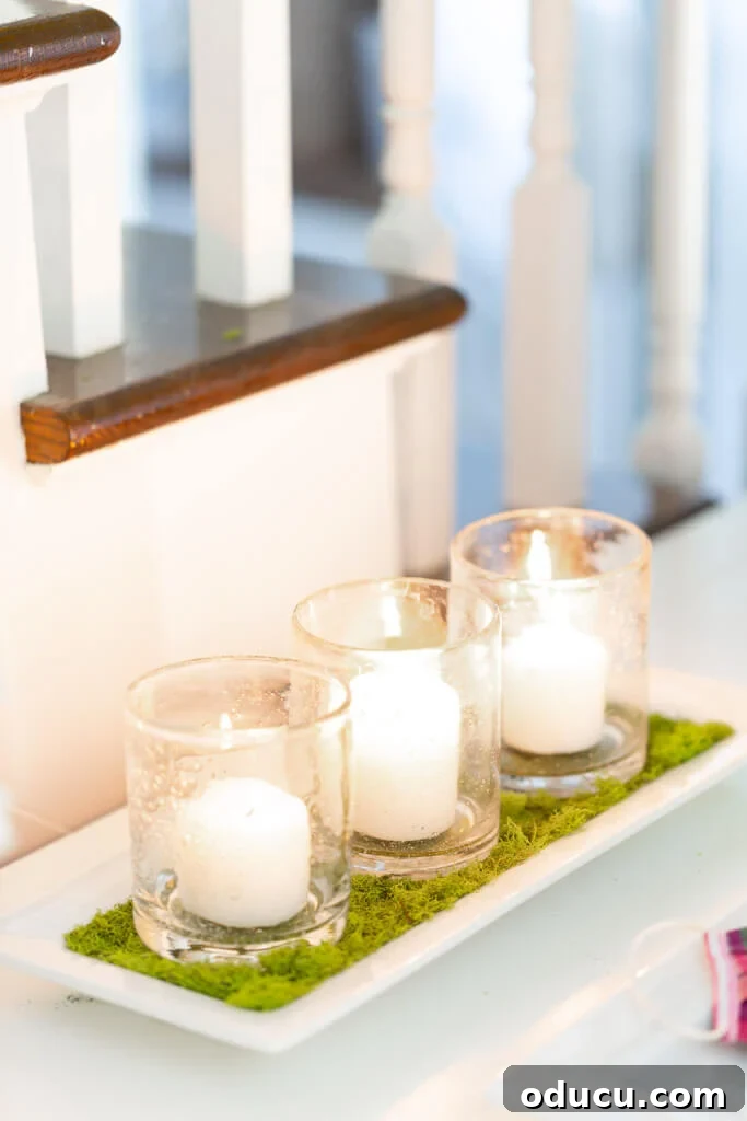 Springtime Glow: DIY Candle Tray 2 Three white candles arranged on a white tray lined with lush green moss, creating a serene spring centerpiece.