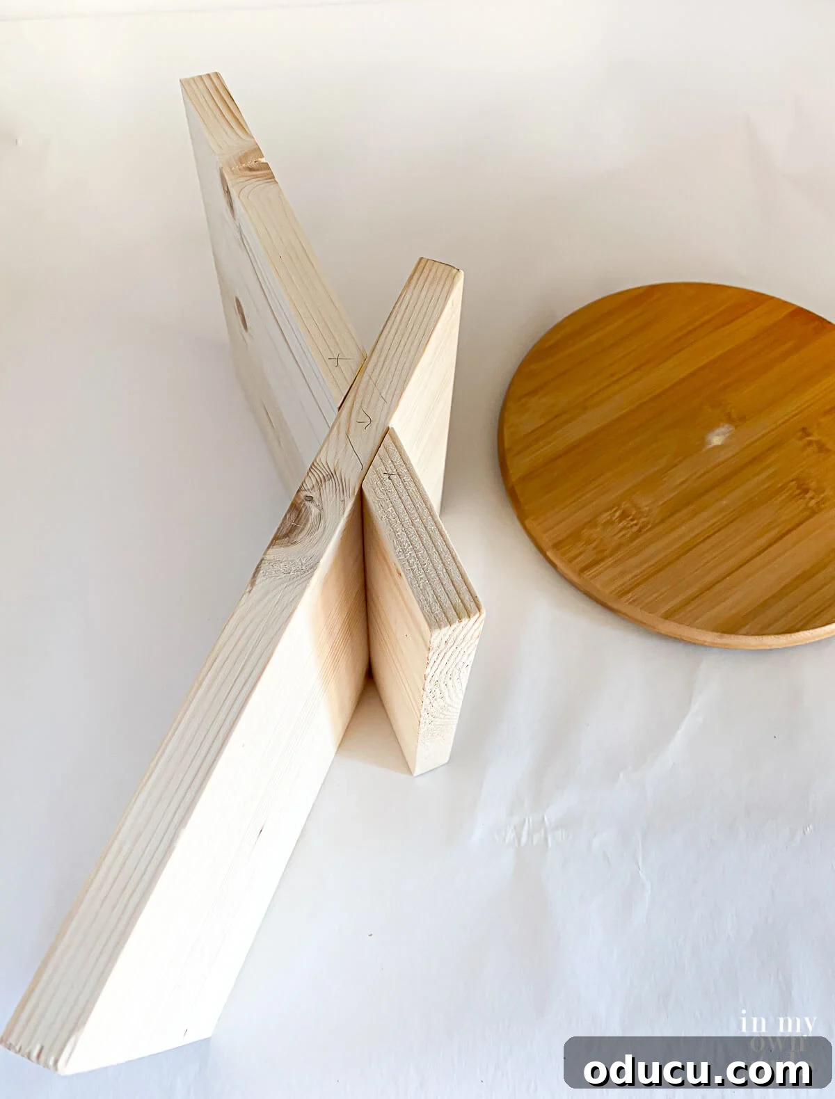 unpainted x shape book stand after being assembled. Shown on its side to see how to put together.