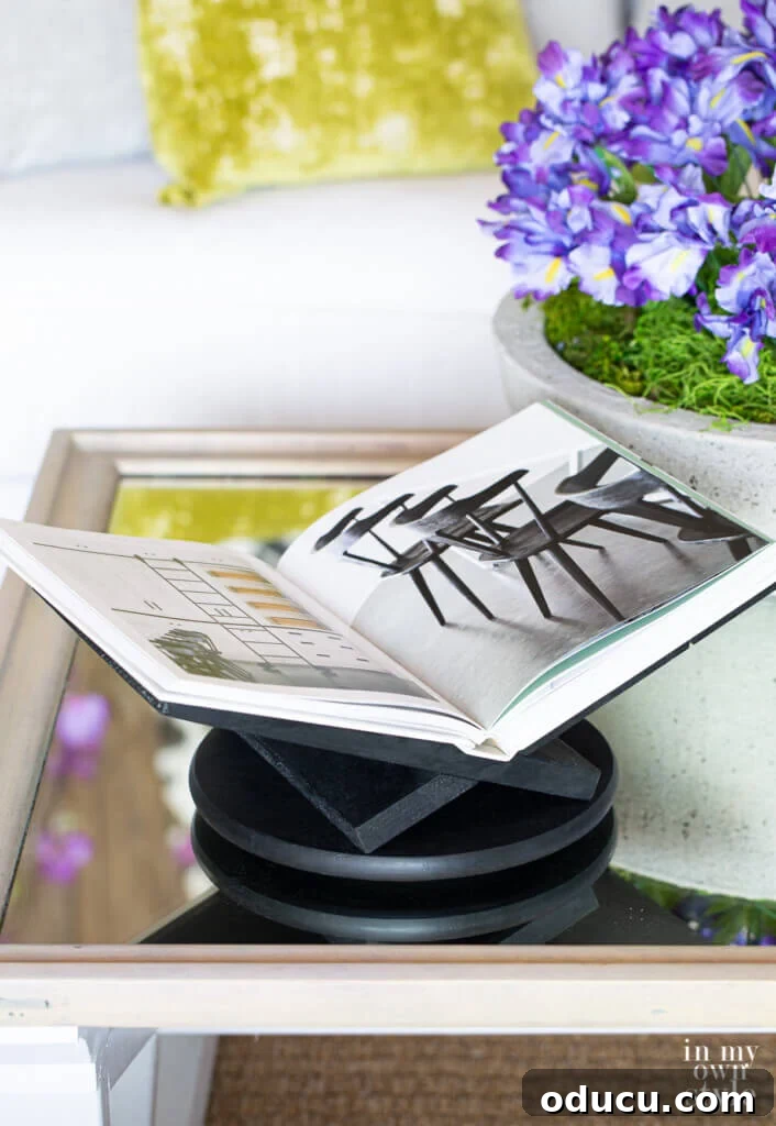 black painted x shape open book holder with book on coffee table.