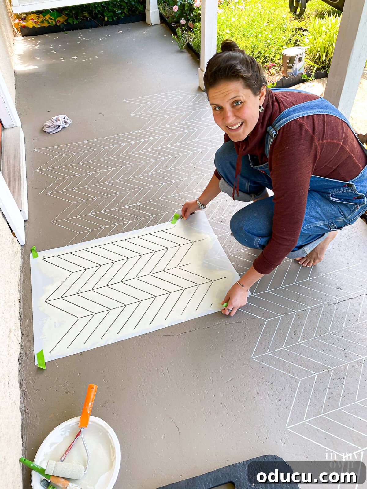 Transform Your Concrete Porch or Patio with Paint and Stencils 10 Lining up herringbone pattern stencil on porch floor and then taping it down.