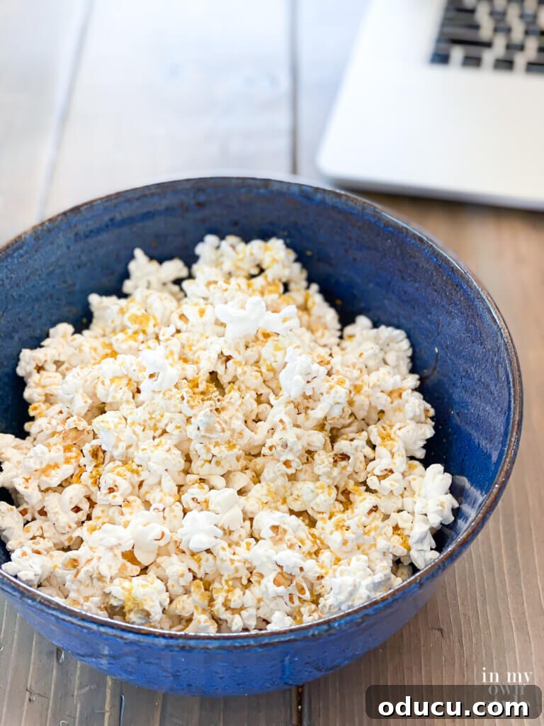 A bowl of freshly made, oil-free air-popped popcorn, seasoned with plant-based ingredients like nutritional yeast and liquid aminos, showcasing a delicious and healthy snack option.