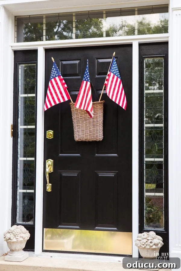 The Style Edit 44 2 A charming front door adorned with a flat-backed rattan hanging basket holding three vibrant American flags, symbolizing patriotic spirit and summer decor.