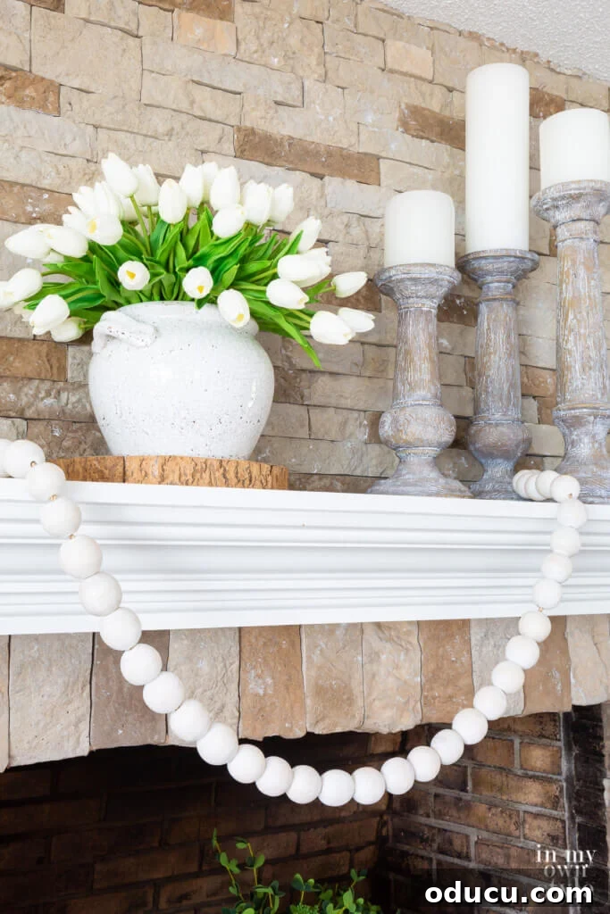 Charming fireplace decorations on a mantel, thoughtfully arranged for summer with a blend of neutral and green accents.